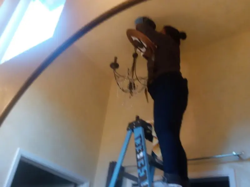 Electrician installing a chandelier in a Casper residence